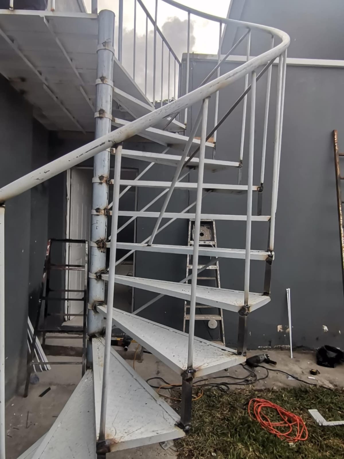 Escalera blanca de caracol con herramientas de instalación visibles