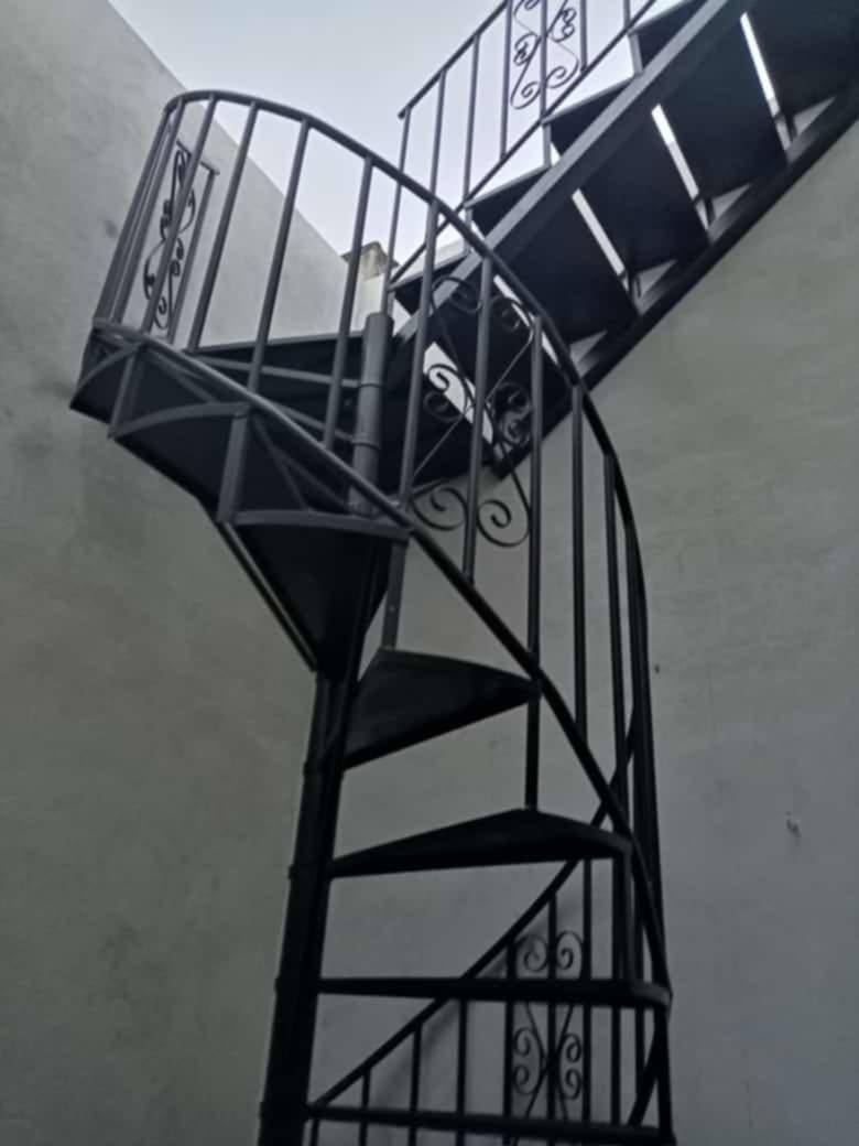 Escalera negra de caracol con pasamanos y baranda ornamental